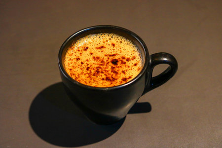 Close-up of Frothy Cappuccino with Cocoa Powder in Black Ceramic Cupの写真素材