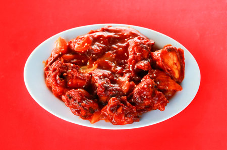 Sizzling Spicy Chicken Manchurian with Sesame Seeds in White Bowlの写真素材