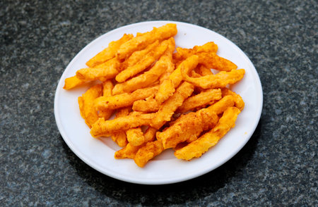Crispy Golden French Fries with Spicy Seasoning on White Plateの写真素材