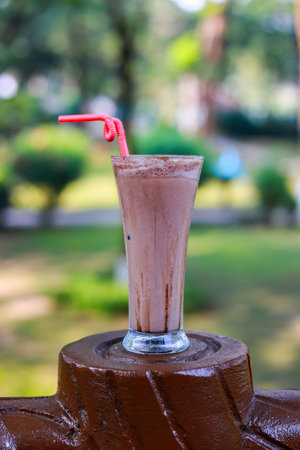 Delicious Chocolate Milkshake with Red Straw and Cocoa Topping Outdoorsの写真素材