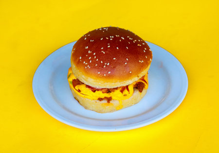 Juicy Beef Burger with Melted Yellow Cheese and Sesame Bun on Yellow Backgroundの写真素材