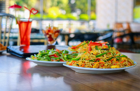 Delicious Vegetable Chow Mein Noodles and Fresh Salad on Restaurant Tableの写真素材