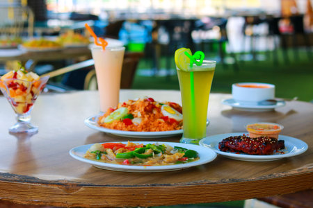 Fresh Fruit Juice Mocktails and Spicy Chicken with Rice on Dining Tableの写真素材