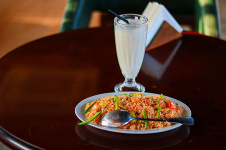 Vegetable Fried Rice Served with Creamy Vanilla Milkshake on Wooden Tableの写真素材