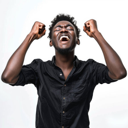 Young african american man with hands up celebrating success on white backgroundの素材