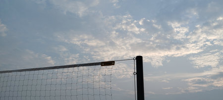 Volleyball net and blue sky with clouds at sunset in summer