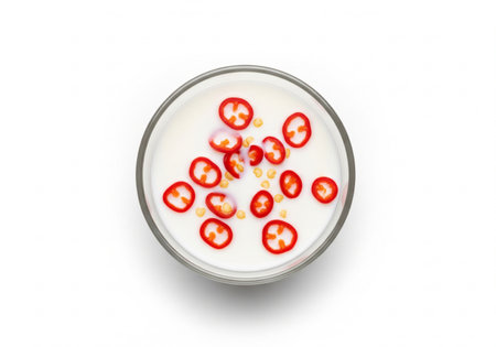 Milk in glass bowl with chili pepper isolated on white background.の写真素材