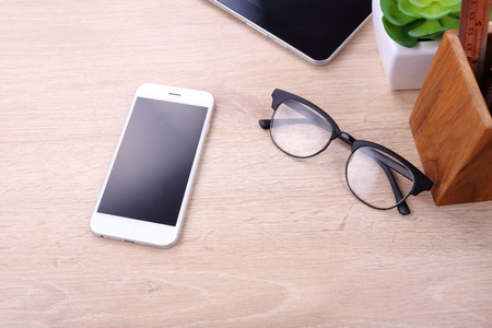 Blank screen smartphone and office supplies on wooden backgroundの写真素材