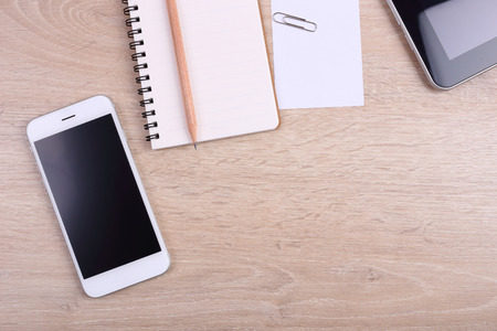 Top view smartphone, tablet and office supplies on wooden backgroundの写真素材