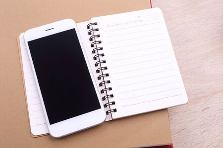 Blank screen smartphone and note book on wooden backgroundの写真素材
