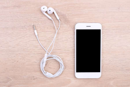 top view smartphone mockup with earphone on wooden backgroundの写真素材