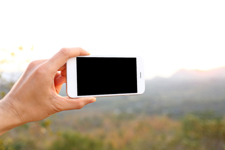 Hand holding mockup smartphone with mountain backgroundの写真素材