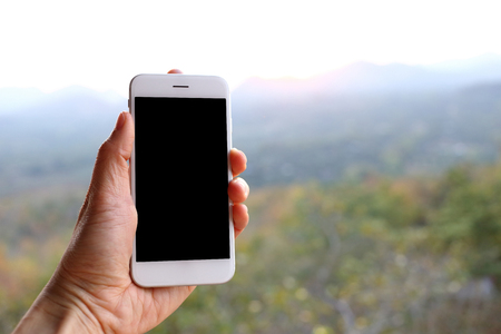 Hand holding smartphone with mountain backgroundの写真素材