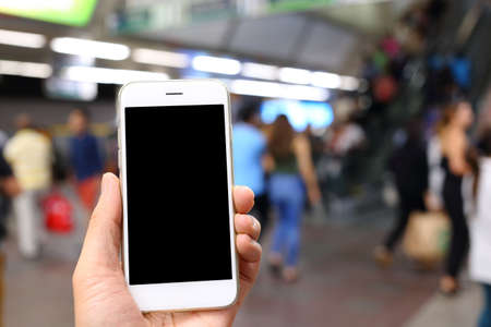 Hand holding smartphone with subway station background
