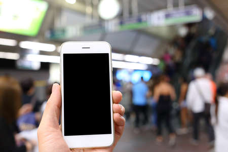 Hand holding smartphone with subway station backgroundの写真素材