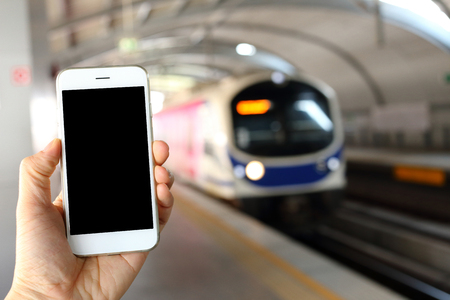Hand holding smartphone with subway station backgroundの写真素材