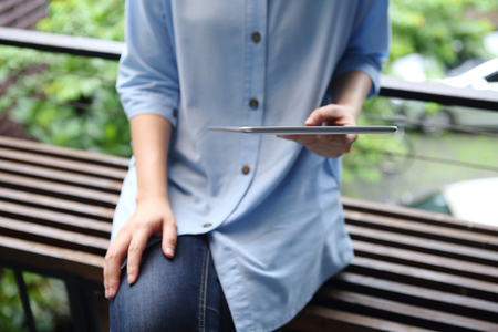 Woman holding and using tablet with office backgroundの写真素材
