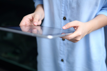 Woman holding and using tablet with office backgroundの写真素材