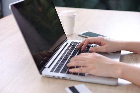 Ecommerce concept, Woman using ecommerce website via laptop with credit cart on wooden desk