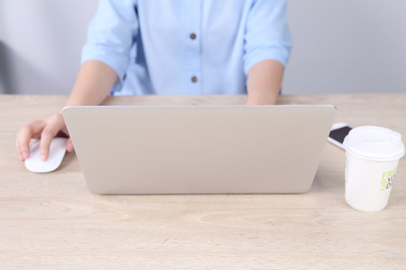 Business woman using laptop with smartphone on wooden desk