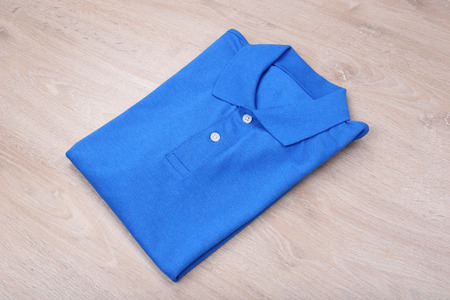 Fold blue polo shirt on wooden backgroundの写真素材