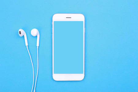 Top view mockup smartphone and earphones on blue pastel backgroundの写真素材