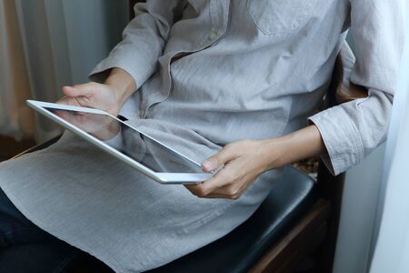 Business woman wear light gray shirt sit on chair with using tablet in cafe