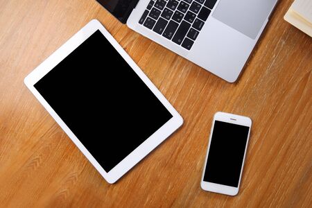Top view tablet mockup with smartphone and laptop on wooden desk
