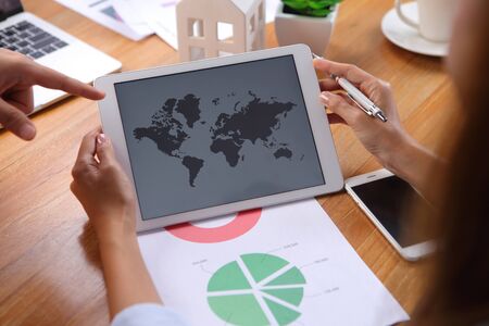 Business peoples discussion using world map and business report on wooden desk