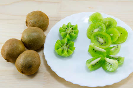 Sliced and whole kiwi on a table and a tableの写真素材