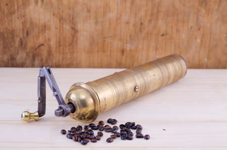 Vintage coffee grinder with coffee grains on a wooden tableの写真素材