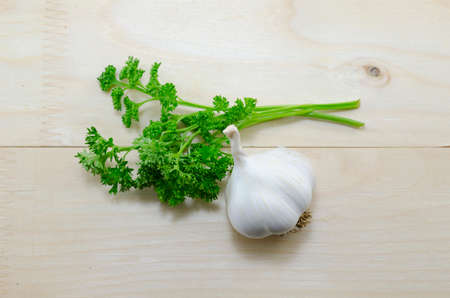 Fresh garlic and parsley on a wooden table