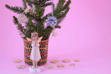 Angel figurine and star decorated fir branches on pinkの写真素材