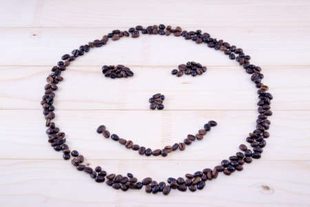 Smiley made entirely out of raw coffee grains, on a table
