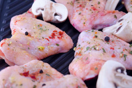 Raw chicken wings covered with spices frying on the grillの写真素材