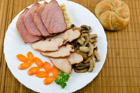 Meat, mushrooms and carrots and a bannock on a plateの写真素材