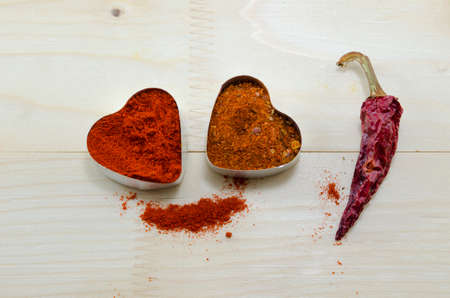 Two pepper hearts and a dried paprika on a wooden tableの写真素材