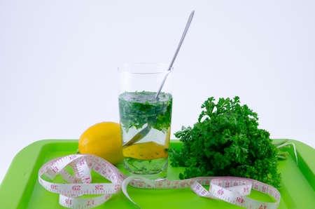 Glass of lemon and parsley on a green tray shot against white backgroundの写真素材
