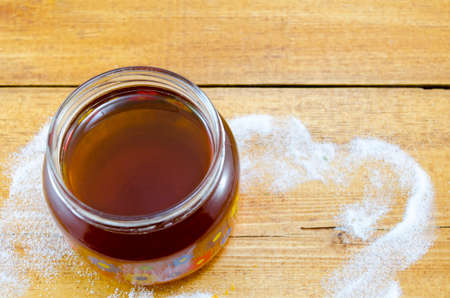 Jar of dark honey on a table decorated with sugarの写真素材