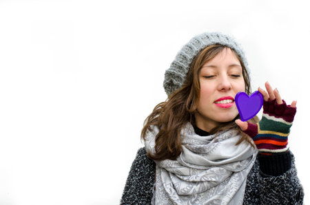 Young girl looking at a heart shaped mirror, isolated on white surfaceの写真素材