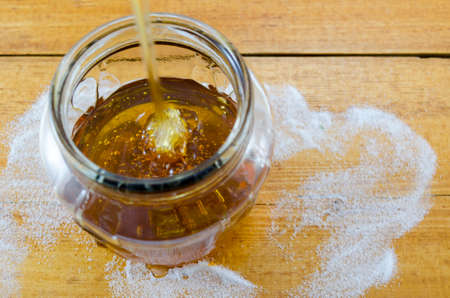 Dark honey dripping into a glass jarの写真素材