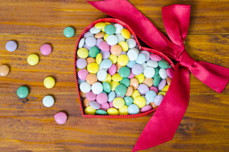 Colorful chocolate pills in a heart shaped boxの写真素材