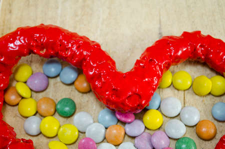Red candy heart and colorful candy bombons on a wooden table, closeupの写真素材