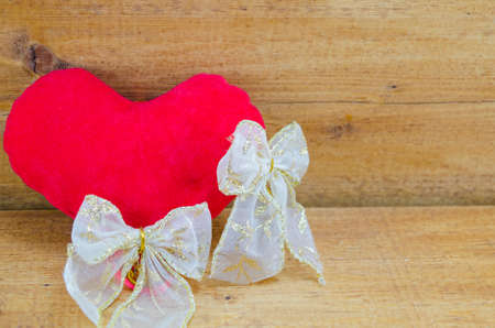 Red stuffed heart and silk ribbons on a wooden tableの写真素材