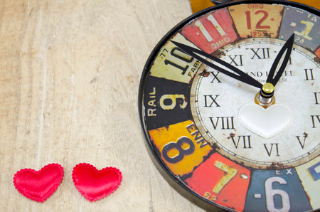 Vintage clock and two hearts on a wooden surfaceの写真素材
