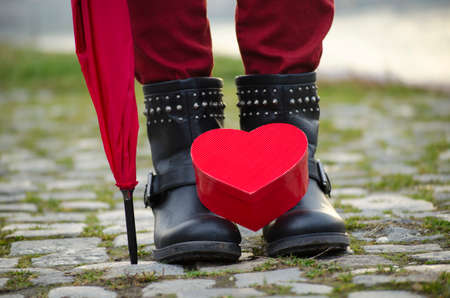 Heart shaped box standing on girl's boots outdoors