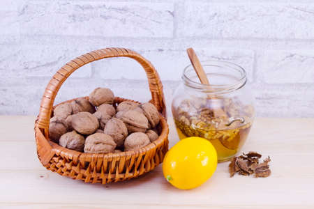 Walnuts in a jar of honey and a lemon on a tableの写真素材