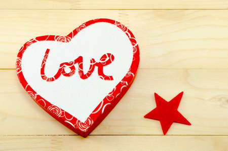 Heart shaped box and a red star on a wooden tableの写真素材