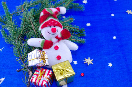 Snowman on a blue Christmas table cloth decorated with a fir branch and bunch of presents and starsの写真素材
