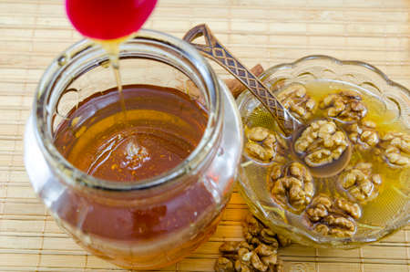 Walnuts and honey in a jar on a wooden tableの写真素材